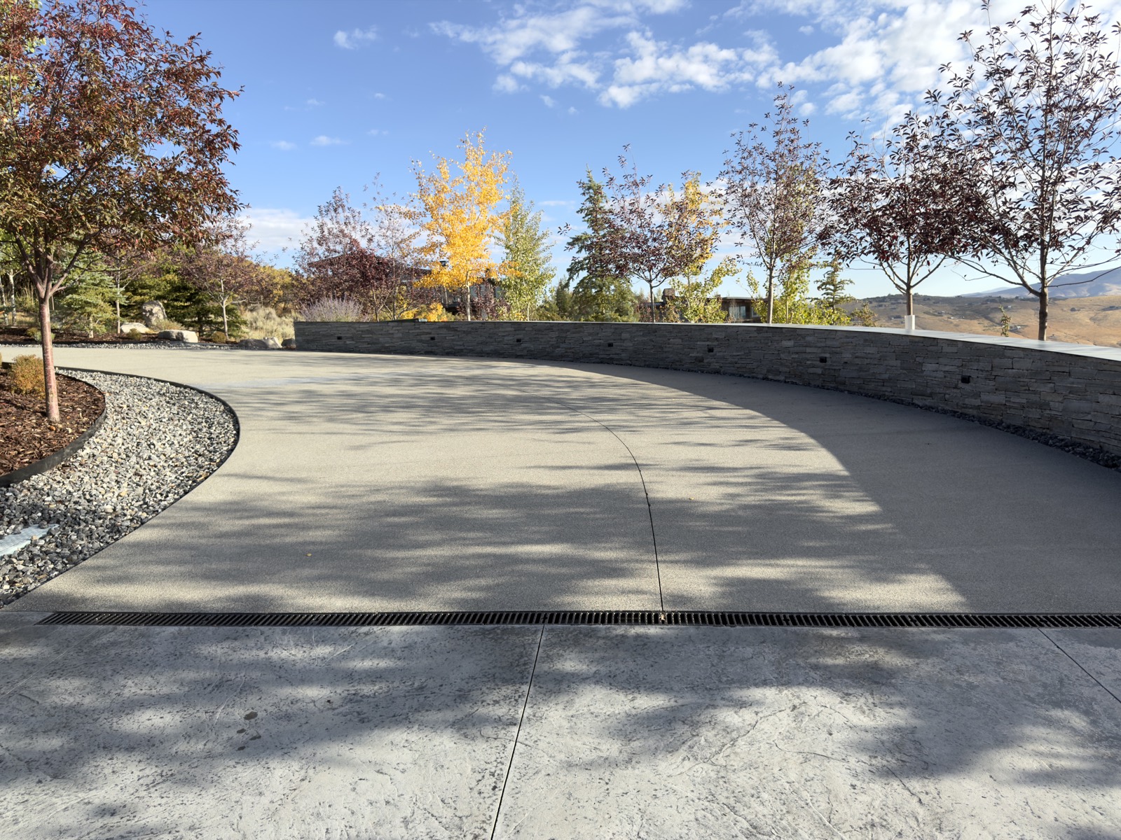 Sealed concrete driveway with stone retaining wall in a Park City mountain setting